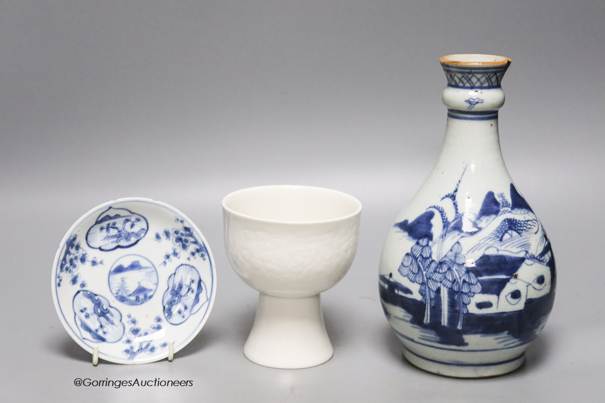 An 18th century Chinese blue and white bottle vase, together with a saucer and blanc de chine stem cup, 22cm